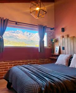 a bedroom with a large bed and a large window at Cabañas Sublime Bolson in El Bolsón