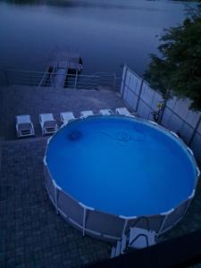 a large blue pool with chairs around it at night at Casa din Golful Dunării in Eşelniţa