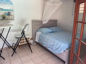 una camera da letto con un letto, un tavolo e una sedia di Studio piscine centre Gosier a Le Gosier