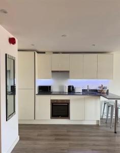 an open kitchen with white cabinets and a table at Birmingham City Centre-2 Mins to Station, City Views in Birmingham