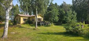 a small yellow house in the middle of a yard at Merenkurkku in Molpe