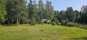 a field with a house in the middle of a forest at Merenkurkku in Molpe