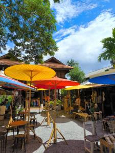 een groep tafels en stoelen met parasols bij Lanna Localstay in Chiang Mai