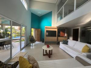 un soggiorno con un divano bianco e una TV di Casa 5 suites a 3 minuntos andando para o mar a Guarajuba