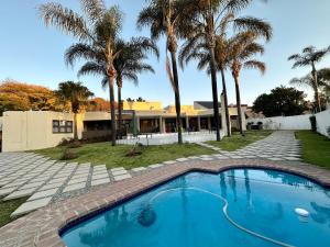 une piscine devant une maison avec des palmiers dans l'établissement The Chapel Luxury Apartments 2, à Johannesbourg