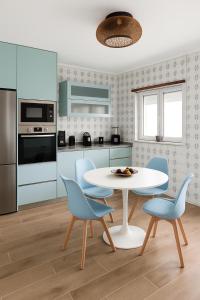 a kitchen with a white table and blue chairs at Paraíso no Furadouro, T2 a apenas alguns passos da praia in Ovar