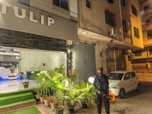 a man standing in front of a building with plants at Tulip Hotel in Karachi