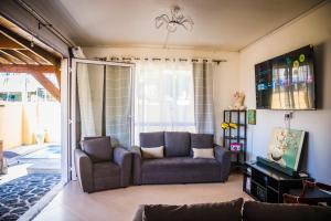 un soggiorno con un divano e una TV di Villa camomilla a Trou aux Biches