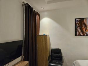 ein Schlafzimmer mit einem TV und einem Stuhl in einem Zimmer in der Unterkunft SBP Hotel in Benin-Stadt