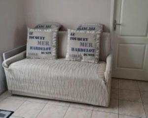 a couch with four pillows on it in a room at Maison plein pied à Quend in Quend