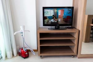 a television on a stand with a vacuum at Flat Alto Padrão no Saint Moritz - Localização Central e Wi-Fi Rápido in Brasilia