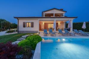 a villa with a swimming pool in front of a house at Villa Kadore in Višnjan