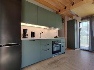 a kitchen with green cabinets and a stainless steel refrigerator at Dom Szumią Wierzby in Szumlin