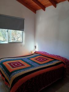 una camera da letto con un letto con una coperta colorata sopra di La Porteña a Cortaderas
