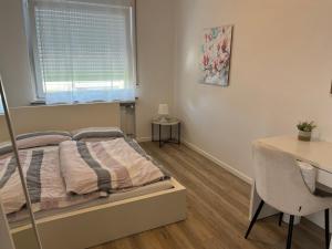 a bedroom with a bed and a desk and a window at Privatzimmer im Reihenhaus nähe Flughafen Hannover Langenhagen in Hannover