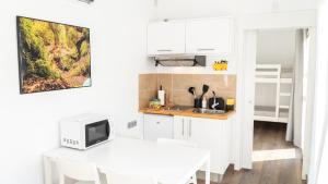 a white kitchen with a table and a microwave at Xeocámping Montañas do Courel in Ribas del Sil