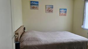 a bed in a bedroom with three pictures on the wall at Maison plein pied à Quend in Quend