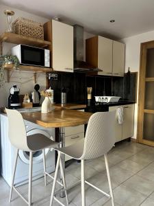a kitchen with a wooden table and white chairs at Studio pratique - Jardin privé in Grabels +5 photos