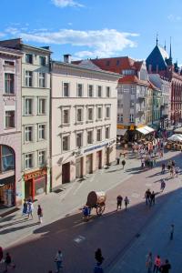 ulica miejska z ludźmi i powozem ciągniętym przez konie w obiekcie Apartamenty Hotelu Pod Orłem w Toruniu