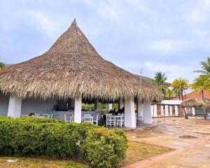 a restaurant with a straw roof with tables and chairs at Beach House Terrazas de Guacuco isla de Margarita in Playa Guacuco