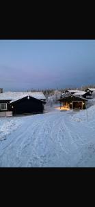 a snow covered road in front of two buildings at Hytte hafjell mosetertoppen in Øyer