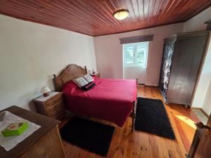 a bedroom with a bed with a red blanket and a window at Casa de Cabecinho- Albufeira do Azibo in Bragança +31 photos