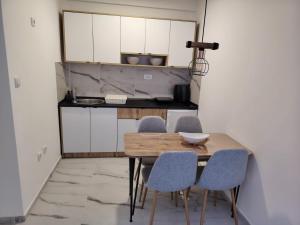 a kitchen with white cabinets and a wooden table and chairs at Mirna obala in Veliko Gradište