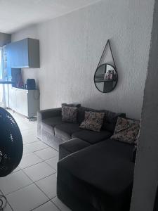 een woonkamer met een zwarte bank en een spiegel bij Condomínio Moradas Club Rios do Pará COP 30 in Ananindeua