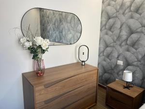 a dressing table with a mirror and a vase with flowers at Bella Room in Gravina di Catania