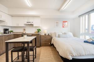 a bedroom with a bed and a table and a kitchen at Top Location - Cozy & Bright MTL studio near metro in Montréal