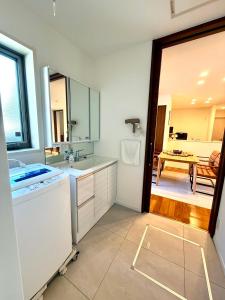 ein weißes Badezimmer mit Waschbecken und Spiegel in der Unterkunft Private stay, fully equipped 45 square meter, Easy access to Disneyland & Airports in Tokio
