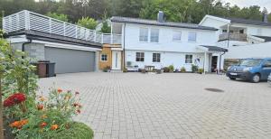 een wit huis met een garage en een geparkeerde auto bij Gjestehus i Tveit in Kristiansand