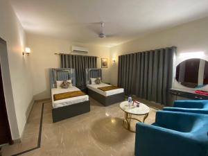 - un salon avec 2 lits et une télévision dans l'établissement Lotus Residency DHA Guest House, à Karachi