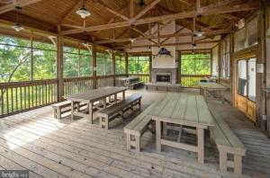 米尔斯伯勒Fabulous on the Fairway!的带野餐桌和壁炉的大型木制门廊