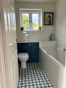 a bathroom with a tub and a toilet and a window at Charmouth Sea House by the beach in Charmouth