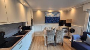 a kitchen with white cabinets and a table with chairs at Beach & Breeze Ferienwohnung mit Terrasse Scharbeutz in Scharbeutz