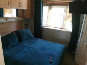 a bedroom with a blue bed and two windows at Beautiful scenery in Startforth