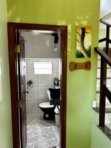 a bathroom with a toilet and a green wall at Casa em Alter do chão - lago verde in Alter do Chao