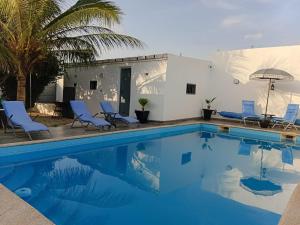 a swimming pool with chairs and an umbrella at Villa JAJA Piscine-Climatisation in Poponguine