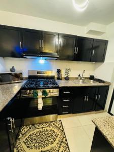 a kitchen with black cabinets and a stove and a sink at Luxurious and comfortable 1 level in Ensanche Savica de Mendoza