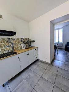 a kitchen with white cabinets and a tile floor at Appartement cosy proche Gare in Roanne