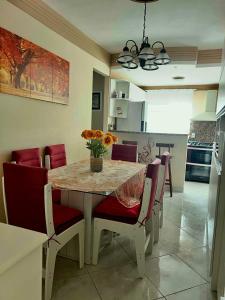 a dining room table with red chairs and a kitchen at Paraíso Tropical em Porto Seguro in Porto Seguro +73 photos
