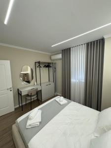 a white bedroom with a bed and a sink at Azure Apartments in Korçë