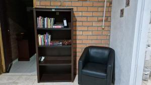 a black chair sitting next to a book shelf at Lacaune Haus in São Francisco de Paula
