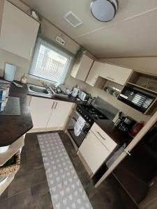 a kitchen with white cabinets and a black counter top at Gold Plus 3 Bed ABI Summer Breeze Modern Caravan with Sea View Pet Friendly in Aberystwyth