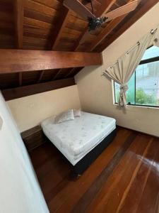 a small bed in a room with a window at Pousada Pérolas de Peruíbe in Peruíbe