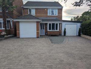 a brick house with two garage doors and a driveway at Spacious 3 bedroom house with games room in Kirby Muxloe