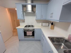 a kitchen with blue cabinets and a sink at Spacious 3 bedroom house with games room in Kirby Muxloe
