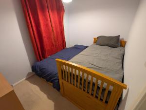 a small bedroom with a bed and a red curtain at Spacious 3 bedroom house with games room in Kirby Muxloe