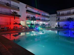 a swimming pool in front of a building at night at Staycation Yakout in Mansouria